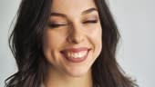 Close-up portrait of young brunette woman on white background smiles...