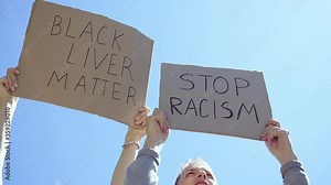 Poster BLACK LIVES MATTER in hands. Stop racism against the blue sky. Stop racism concept.