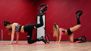 Two beautiful sports girls perform an active fat-burning workout jumping like a kango jump in special fitness shoes. Cardio workout for endurance. Exercise for the muscles of the buttocks