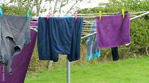 Closeup of a rotary washing line on grass, turning in the wind as the clothes dry. Stock ビデオ