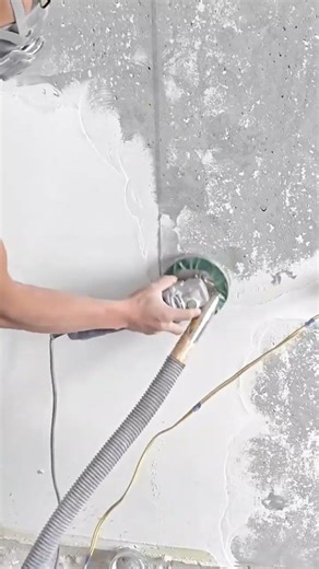 Using a handheld grinder to smoothly finish a concrete wall surface