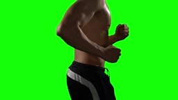Side view of sporty man with muscle body running in place on green...