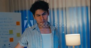 Young Asia male use computer remote feel tired from overwork take rest raise arm stretch muscle in living room at home office overtime night. Work from house, remotely digital nomad and Gen Z talent.