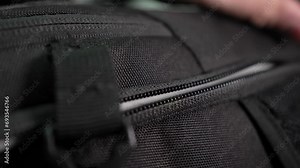 Close-up of male hands closing a suitcase and locking it. A man is packing a suitcase in preparation for a trip. A Black Travel Backpack With A Zipper. shot of unzipping and zipping bag.