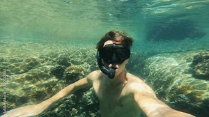 Caucasian man snorkels underwater capturing his adventure on camera marine activities joy of exploration. Underwater footage of man snorkeling recording his underwater experience marine adventures.