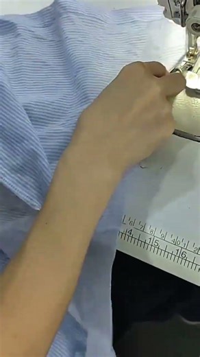 sewing blue striped fabric using an industrial sewing machine for professional clothing production