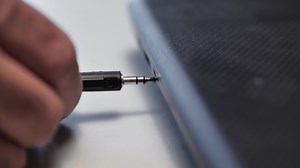Headphone wire inserted into laptop. Media. Close-up of man inserting wire with headphone connector into laptop. Connecting headphones to laptop via wire
