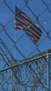 9-star USA flag waving behind a mesh - Free Stock Video