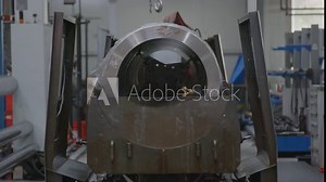 A large hydraulic cylinder being oiled by a honing tool. The spinning honing tool slowly spins forwards and lubricates the large metal pipe while finishing the internal surface.