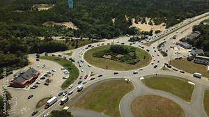 Roundabout traffic on the ring before entering the Bourne Bridge over the Cape Cod Canal. Landscape design in Cape Cod style. Shooting from a drone from a bird's-eye view.