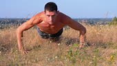 Young Athletic Man with a Bare Torso Performs Pushups on Nature. Man...