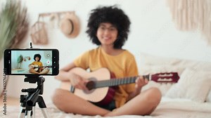 Art Bloggers, Online Lesson Recording, Woman Blogger, Playing Guitar. Afro american woman blogger playing guitar while sitting on bed at home