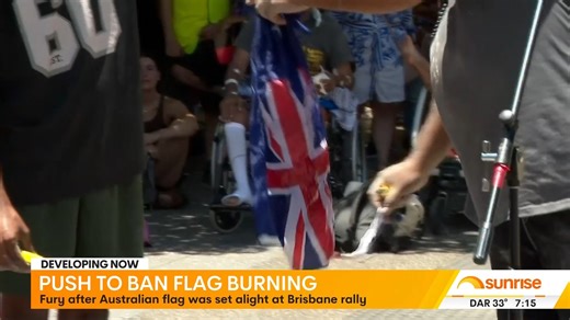 Federal Education Minister Jason Clare responds to the burning of an Australian flag at an Invasion Day protest in Brisbane on Australia Day, calling the act divisive while noting existing state laws already empower police to take action. Clare also discusses proposals for mandatory sunscreen application in schools and the Northern Territory's plan to enforce compulsory singing of the national anthem at school assemblies. | Sunrise