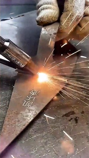 marking the triangular metal sheet using a handheld laser tool with many bright orange sparks flying