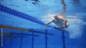 Muscular man under water in a swimming pool in super slow motion
