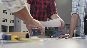 Architects discussing building plans, pointing at blueprints, and working together on a project with a scale model in an office setting