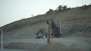 Earth mover cleans up soil for road renewal. Heavy duty mining machine at work. Quarry harvester unit with heavy equipment. Road constraction, repairing. Slow motion