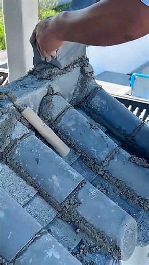 Worker lays traditional clay tiles using cement for solid roof construction