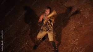 Funny guy playing the trumpet in a cave. Crazy guy funny playing the trumpet and dancing.