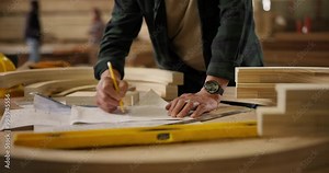 Carpenter, hands and pencil with drawing for construction, furniture or project. Closeup of person with design, wood and tools in a creative carpentry workshop for manufacturing, art or product craft