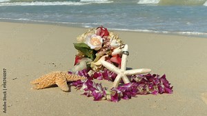 Wedding rings on the starfish, Lei and bouquet, beach love concept. Closeup of two bands in flower heart for casual marriage celebration Oahu Hawaii.