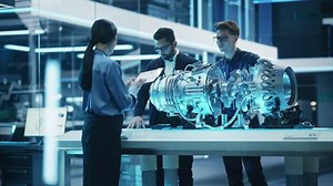 Diverse Multiethnic Team of Industrial Engineers Gathered Around a Table With a Prototype Turbine Engine. Scientists Use Laptop Computer to Research, Develop and Program the Futuristic Motor.