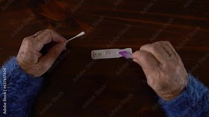 Close-up of caucasian grandma placing the sample into a buffer dropper for seft detection of coronavirus at home. Grandmother using PCR test after come back from crowd and meeting people. Old woman