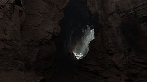 A cave entrance with a waterfall coming out of it