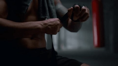 clip-3980232425-unrecognizable-muscular-man-wrapping-hands-boxing-tape