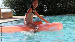 Children at the pool playing, little girl on top of inflatable mattress