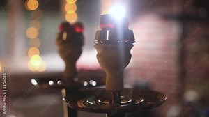 View of Hookah with candles and smoke on a table, hookah lounge with young people smoking in the background, shisha party club concept