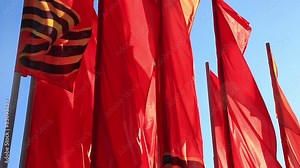 Red flags flutter on a wind against the sky
