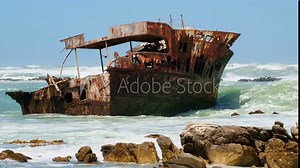 Rusty sunken shipwreck stuck in shallows of rugged Cape Agulhas coastline