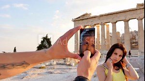 Beautiful Greek woman poses for a photo in front of a Greek temple.