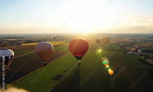 A drone shot flying through clouds that reveal many hot air balloons drifting in the sky