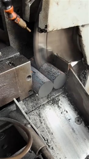 industrial metal cutting machine using a circular saw blade to slice through thick steel cylinders