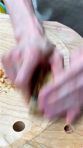 smoothing a circular wooden board with a small hand plane to create a uniform and polished surface