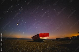 Astro Time Lapse - Lone Red Boat on a beach stars move across the sky