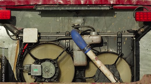 Close-up of a custom off-road vehicle's cooling system. Muddy radiator, fans, and dented frame show wear from intense racing. Gritty, mechanical, powerful mood