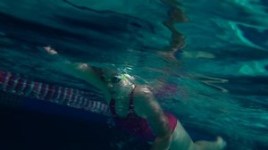 Amateur Swimmer Practicing in Water Swimming pool. Female swimmer practicing flip turn. Underwater view. Night shot.