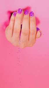 A girl's hand spilling glitter on a pink background - Free Stock Video