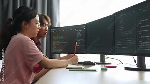 Slow motion back end software developer engineer for computer programming working together on debugging writing computing code, solving complex algorithms display on monitor in office. Burgeoning