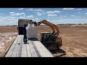 Unloading a super sack of bentonite from flatbed truck using a skid steer