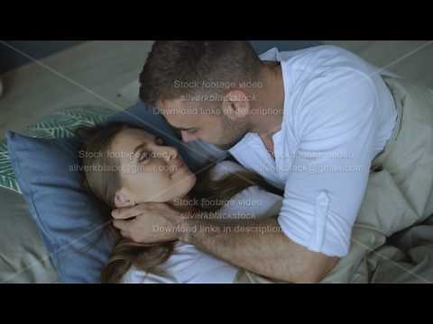 Young beautiful and loving couple wake up at the morning. Attractive man kiss and hug his wife in