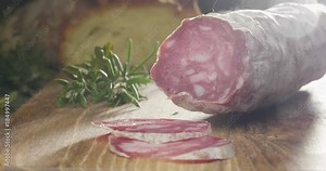 Super slow motion macro of a middle aged chef cutting salami and prosciutto ham from parma with a knife on a wood board (close up) Stock Video