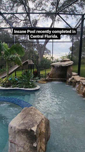 Insane Pool recently completed in Central Florida. This backyard has a huge grotto, a waterslide, a big spa, a swim-up bar, a screened enclosure, a fire pit, and a lifeguard stand. #insanepools #lucaslagoons #pool #poolbuilders #backyard #luxurylife #waterslide | Lucas Lagoons