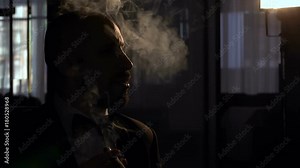 Silhouette serious man with a cigar who blows a lot of smoke, slow motion.
