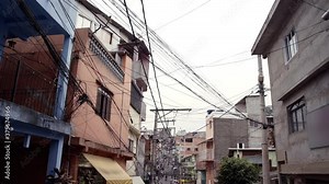 Cityscape of the one of the largest slums of Sao Paulo, Brazil in Latin America. In the scene brick houses in a narrow street covered with power cables in a poor neighbourhood.
