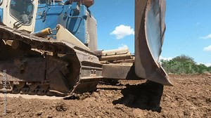 Earth movers leveling ground on road construction in field with dust
