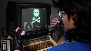 Upset, mad computer geek getting frustrated and hitting old concept computer from 70s 80s because of loosing and seeing game over sign